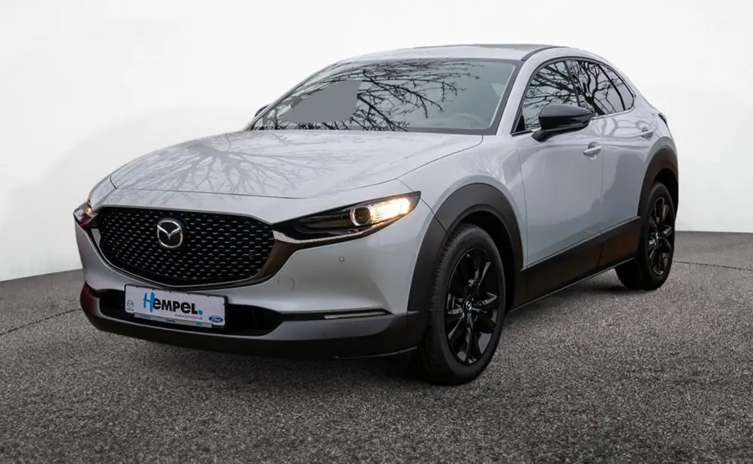 Seitliche Front eines Mazda CX-30 in der Farbe ceramic-white, der auf dem Hof des Autohauses Hempel in Braunschweig steht.